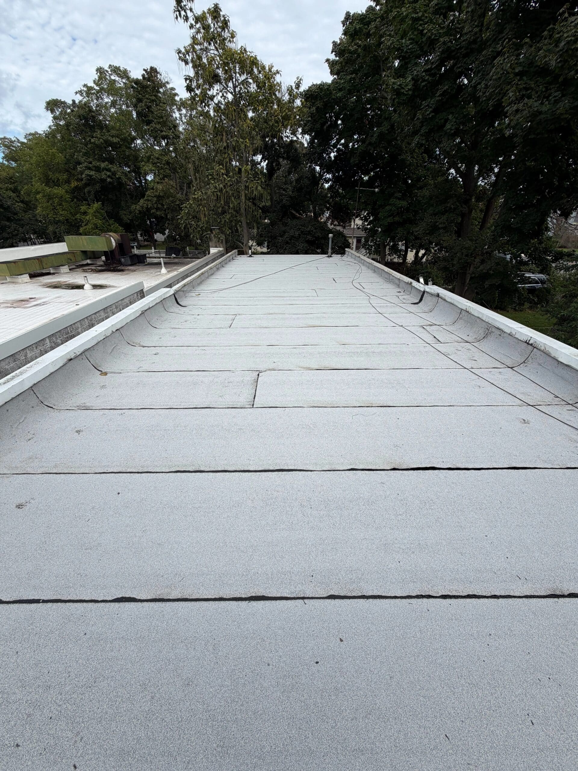 Completed commercial flat roofing in Islip, NY, showing gray roofing sheets, sealed seams, and parapet flashing
